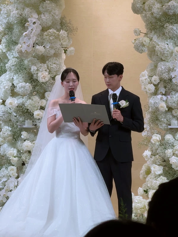 서약하는 두 사람을 뒷자리 하객이 넓게 찍은 장면